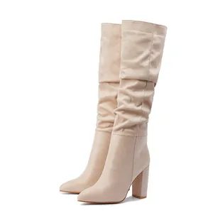 Stylish beige slouchy high-heeled boots with pointed toe and block heel on white