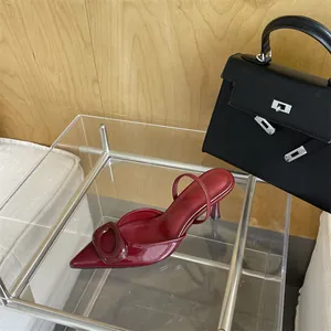Detailed view of the burgundy patent leather pointed-toe pump with decorative buckle