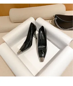 Detailed view of black patent leather pumps with metallic silver toe caps