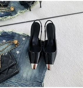 Detail shot of elegant black patent leather slingback heels with metallic silver pointed toe.
