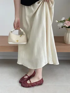Close-up detail of burgundy embroidered mesh Mary Jane flats paired with a satin skirt
