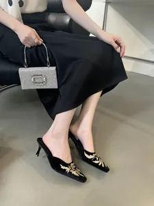 Primer plano de elegantes mulas de terciopelo negro con exquisito bordado floral en modelo