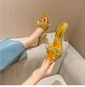 Mules dorées à talons hauts élégantes avec fleurs 3D et brides en PVC transparentes.