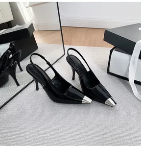 Detail of black patent leather slingback heels with metallic silver pointed toe caps.