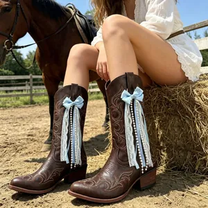 Western cowboy boot ribbon decoration with blue bows, white lace tassels, and pearls