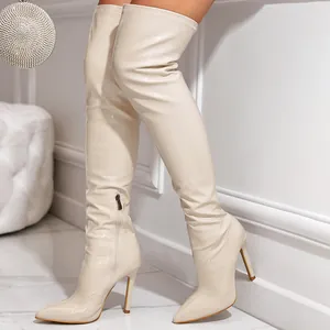 Macro detail of cream thigh-high boots featuring crocodile texture and stiletto heels