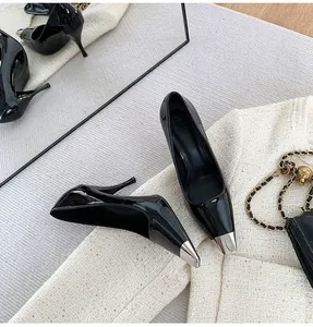 Detail shot of elegant black patent leather pumps with a metallic silver pointed toe.
