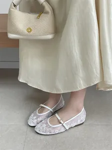 Elegant white embroidered mesh Mary Jane flats worn by model with flowing skirt