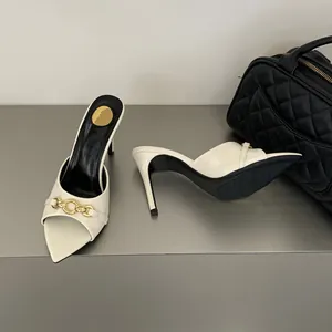 Dettaglio di eleganti sabot bianchi a punta con fibbia a catena dorata decorativa