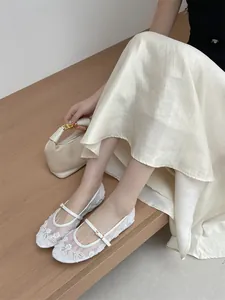 Close-up of white mesh flat shoes with elegant floral embroidery and Mary Jane strap