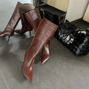 Πλαϊνή όψη από κομψές καφέ δερμάτινες μπότες με μυτερή μύτη και λεπτό ψηλό τακούνι