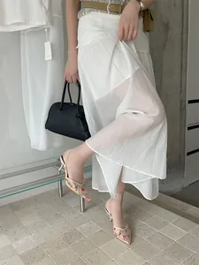 Vista de detalle de zapatos slingback de malla bordada con flores y falda blanca