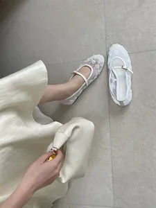 Close-up of white mesh flat shoes with delicate floral embroidery and beaded details