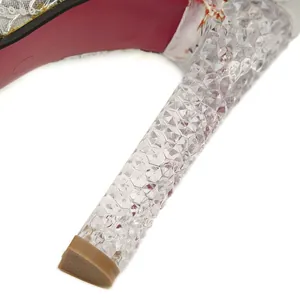 Gros plan d'un talon haut en cristal transparent avec un motif en facettes de diamant