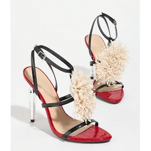 Detail view of red and black high heels with cream pom-pom and metallic heel