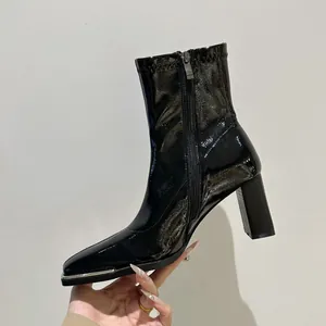 Side view detail of black patent leather ankle boots with thick block high heels