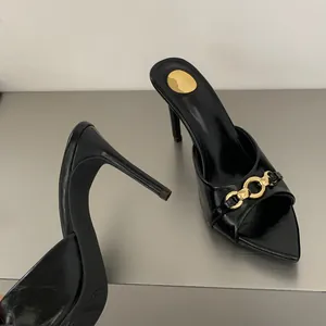 Dettaglio di sabot neri con tacco a spillo e decorazione con elegante catena dorata