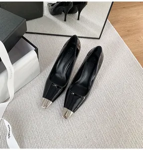 Close-up of black patent leather stiletto pumps with silver pointed metal toe caps.