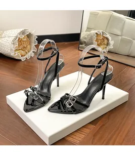 Detail shot of black patent leather stiletto sandals with crystal-embellished buckles.