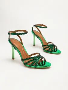 Detailed macro view of emerald green metallic stiletto sandals with rhinestone straps