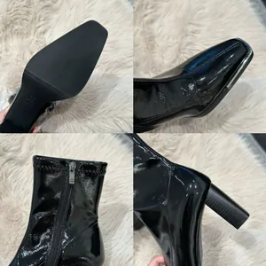 Detail view of black patent leather chunky heel ankle boots with side zipper.