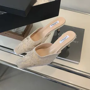 Vista detallada de elegantes mules bordados beige con tacón fino y motivos florales