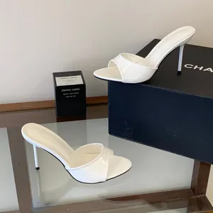 Close-up of white patent leather mule sandals featuring a 9cm stiletto high heel