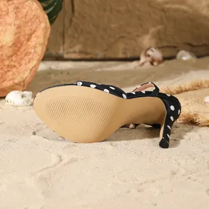 Detailopname van de zool en naaldhak van een elegante sandaal met stippen op zand