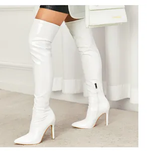 Detailed view of elegant white patent leather over-the-knee boots with high stiletto heels