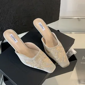 Detalle de mules beige bordados de flores vintage con punta cuadrada y tacón fino