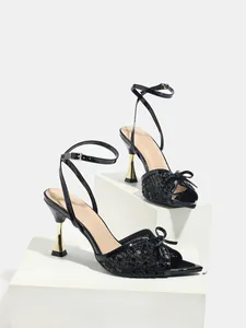 Dettaglio di scarpe da ballo latino nere con paillettes, tacco dorato ed elegante fiocco decorativo