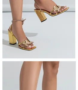 Detailed view of gold block heel sandals with rhinestone butterfly decoration on model