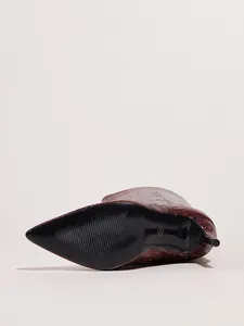 Detailed view of the black sole and red snake print texture of stiletto boots.