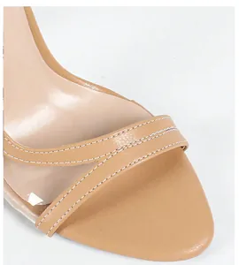 Detailansicht der weißen Nähte auf hellbraunem Leder und klaren PVC-Riemen für Damensandalen