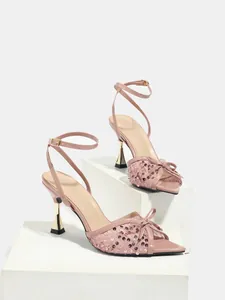 Vista completa di sandali da ballo latino rosa con paillettes esposti su piedistalli bianchi