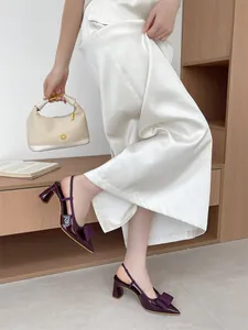 Close-up of elegant purple patent leather slingback pumps featuring a bow and chunky heel