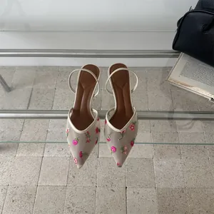 Primer plano de elegantes sandalias francesas de malla con bordados florales vintage.