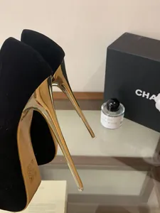 Elegantes Detail von schwarzen Samt-Stilettos mit glänzenden metallischen Gold-Absätzen