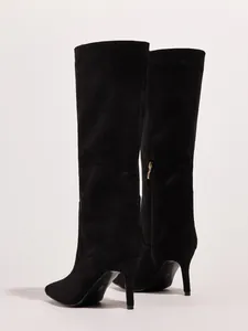 Side view of elegant black suede knee-high boots with thin high heels and pointed toe.
