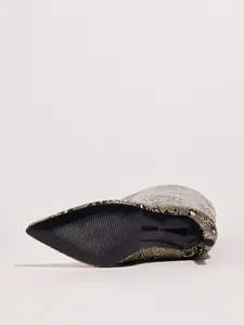 Detailed view of the black textured sole and slim stiletto heel of a snake print boot