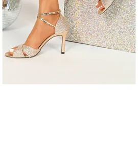 Detailed side view of champagne gold glitter high heel sandals featuring a thin stiletto heel