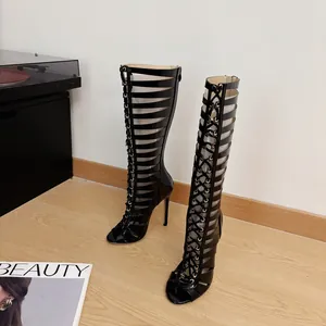 Detailed view of sexy black hollow lace-up gladiator stiletto boots on wooden floor