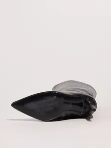 Close-up detail of snake skin texture and non-slip sole on pointed toe high heel boots