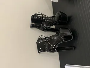Detailed side view of black patent leather platform boots with metal chains and rivets