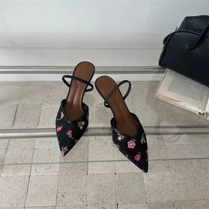 Detalle de cerca de sandalias de malla negra con elegantes bordados florales rosas