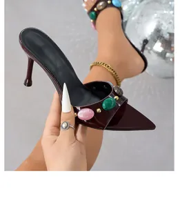 Close-up of burgundy patent leather stiletto sandals with colorful stone embellishments