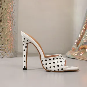 Side view of elegant white high-heeled mule sandals with classic black polka dots