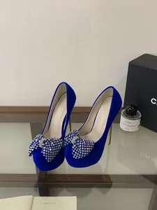 Detailaufnahme von kobaltblauen Samt-High-Heels mit funkelnder Strass-Schleife