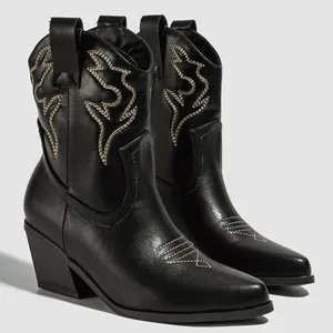 Macro detail of black western cowboy ankle boots featuring elegant white embroidery