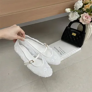 Close-up of white embroidered mesh ballet flats with delicate floral beadwork detail